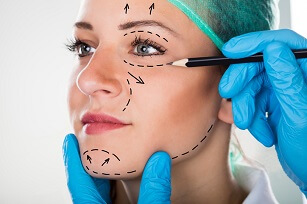 Close-up Of A Surgeon Drawing Perforation Lines On Young Woman's Face For Plastic Surgery